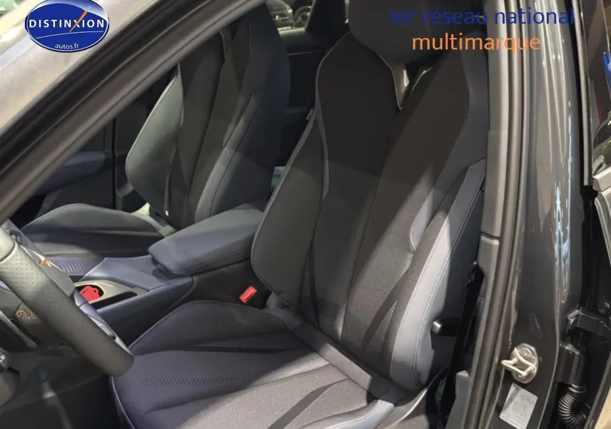 Vue intérieure côté conducteur de la CUPRA Terramar 2025 gris, sièges sport et accoudoir central visible.