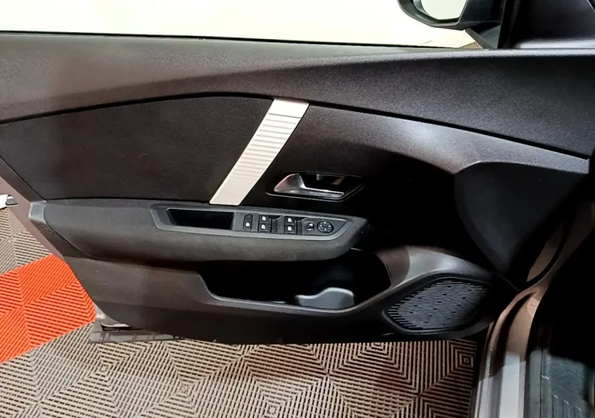 Vue intérieure du panneau de porte côté conducteur de la Citroën C4 2021 gris foncé avec commandes électriques et haut-parleur intégré.