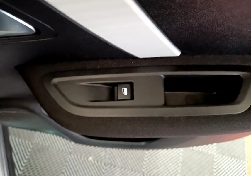 Détail de la poignée intérieure de porte arrière droite de la Citroën C4 gris foncé, bouton de verrouillage visible.