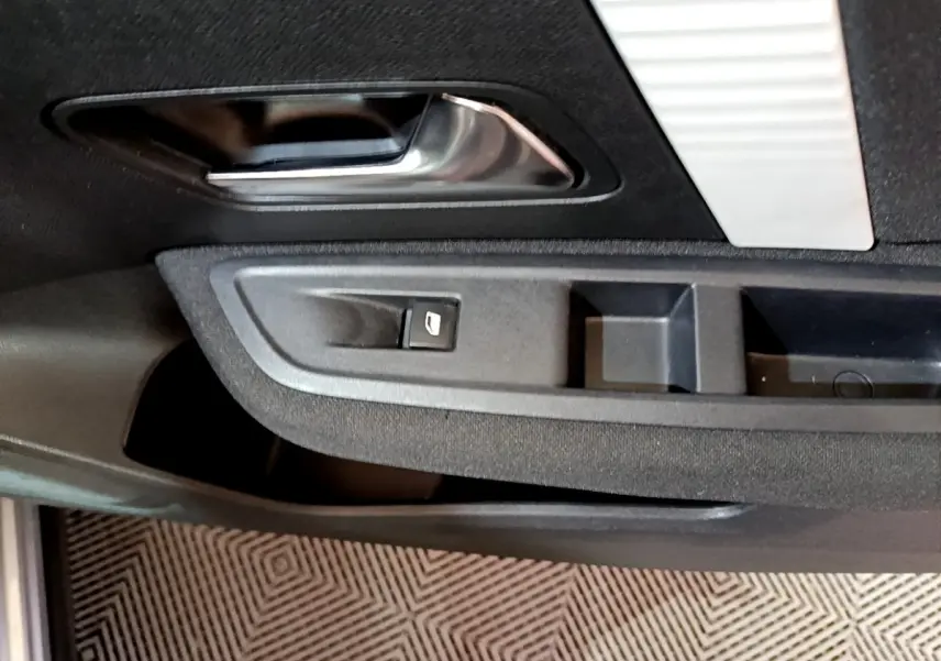 Détail de la porte côté conducteur de la Citroën C4 gris foncé, avec poignée intérieure chromée et commande de vitre électrique.