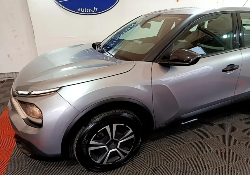 Vue 3/4 avant droit d'une Citroën C4 gris foncé avec jantes noires et phares LED distinctifs.