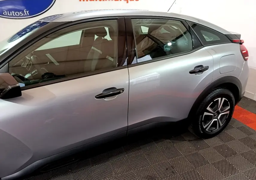 Vue latérale côté gauche d'une Citroën C4 gris foncé, mettant en valeur les lignes fluides et les jantes au design moderne.