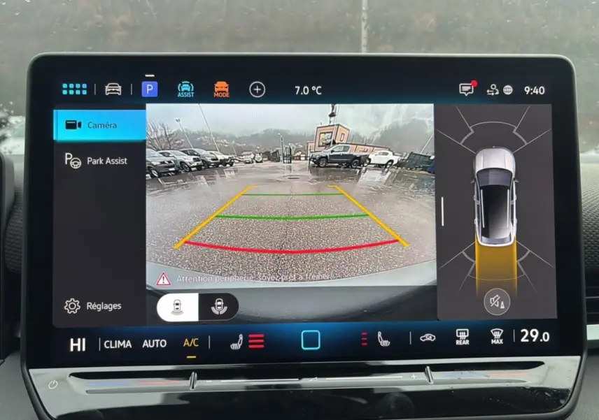 Écran de caméra de recul du Volkswagen T-Roc gris loup montrant une vue arrière avec lignes de guidage colorées.