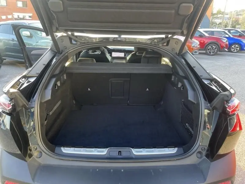 Coffre ouvert vu de l'arrière d'une Peugeot 408 Hybrid 136 cv GT noir métal, montrant l'espace de chargement et l'intérieur.