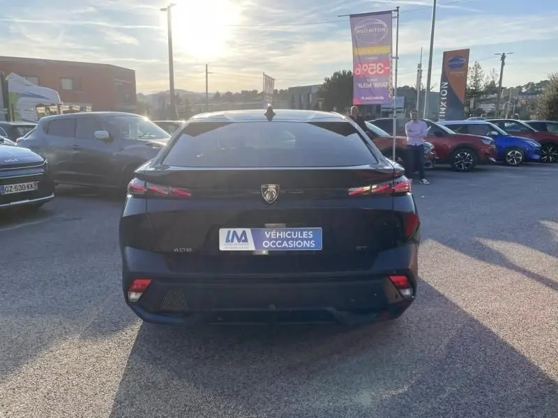 Vue arrière d'une Peugeot 408 Hybrid 136 cv GT noire métal 2024, avec feux arrière LED et logo Peugeot visible.