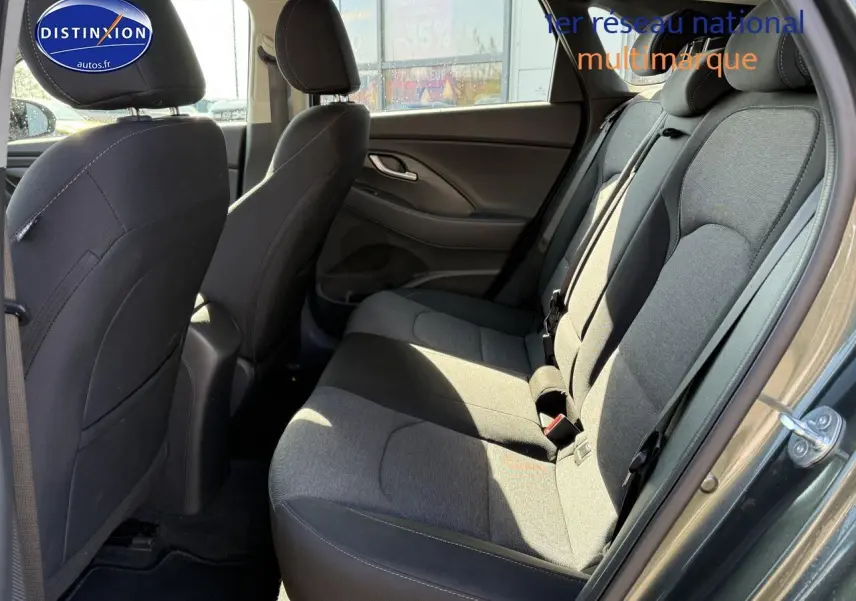 Vue côté gauche de l'habitacle arrière gris anthracite de la Hyundai i30 2024 avec sièges tissu et ceintures visibles