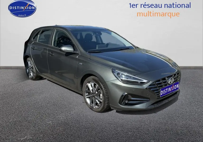 Hyundai i30 gris anthracite vue 3/4 avant droit avec jantes alliage et calandre hexagonale distinctive.