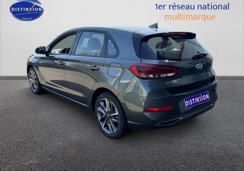 Vue 3/4 arrière droite d'une Hyundai i30 gris anthracite avec jantes alu et feux arrière LED visibles.