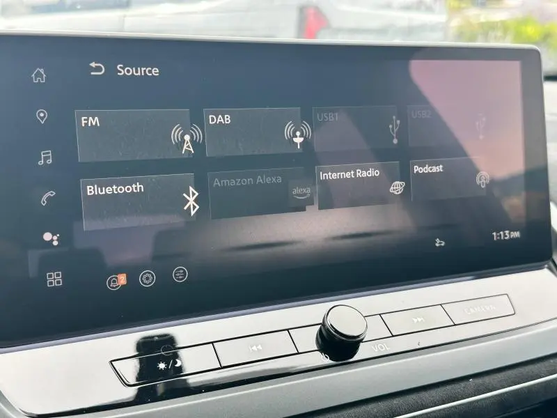 Écran tactile central du Nissan Qashqai e-POWER 2025 affichant les sources audio avec commandes sous l'écran.