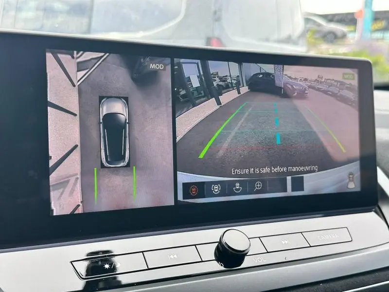 Affichage écran intérieur du Nissan Qashqai e-POWER 2025 montrant la caméra de recul et vue aérienne du véhicule gris en stationnement.