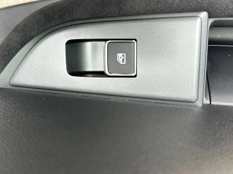 Bouton d'ouverture du coffre en gros plan sur la planche de bord noire du Nissan Qashqai e-POWER 2025.