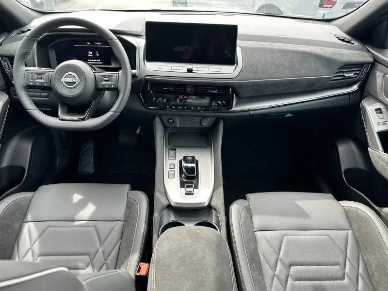 Vue intérieure avant du Nissan Qashqai e-POWER 190ch N-Design 2025, avec tableau de bord moderne et sièges en cuir noir.