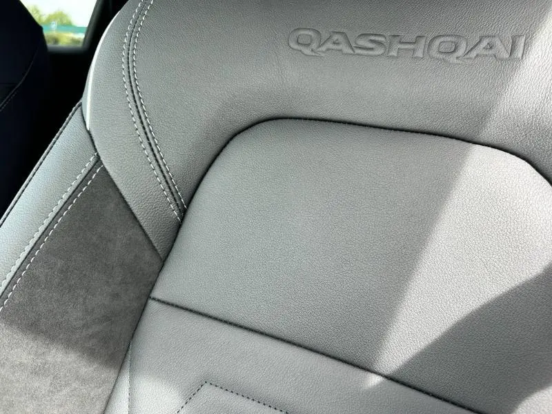 Gros plan sur le siège avant gris clair du Nissan Qashqai e-POWER 2025 avec logo QASHQAI embossé sur l'appuie-tête.