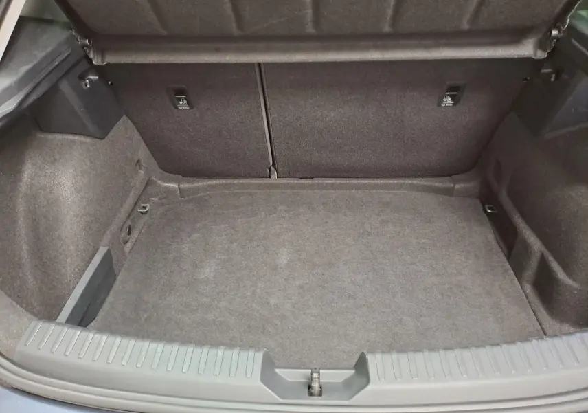 Coffre ouvert vu de l'arrière d'une SEAT LEON gris magnétique, montrant un espace de chargement vide et propre.