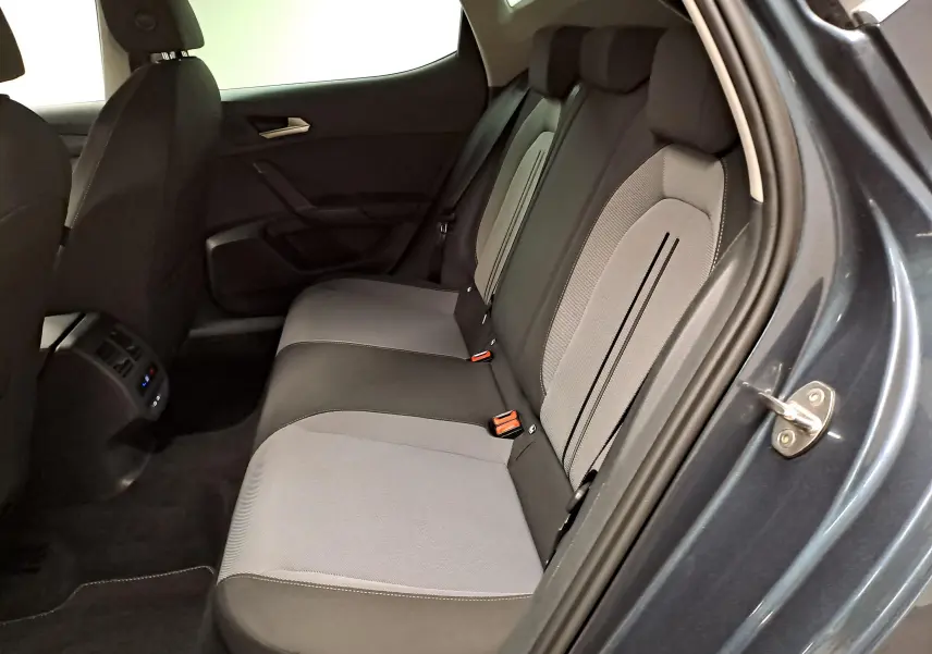 Vue intérieure côté droit des sièges arrière gris clair et foncé du SEAT LEON 1.5 eTSI Hybrid 2025 en Gris Magnétique.