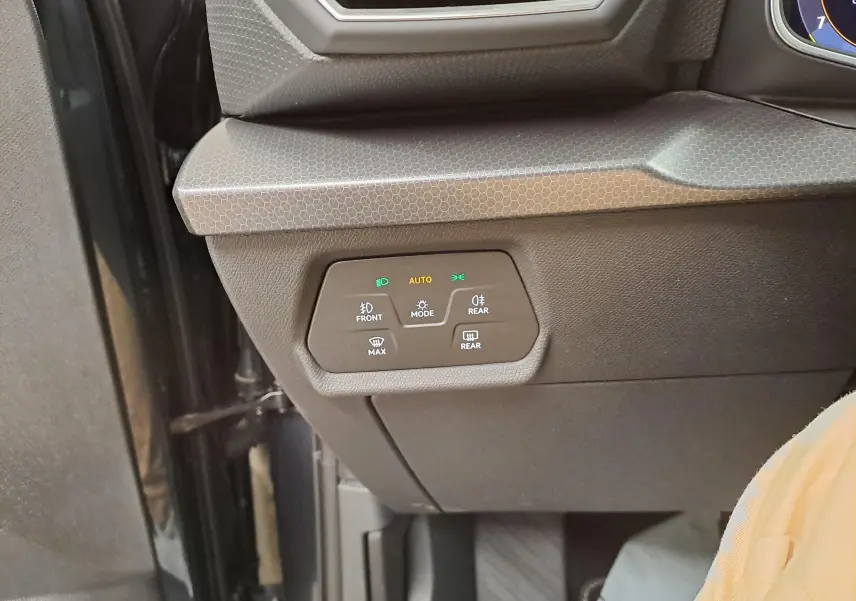 Détail du tableau de bord côté gauche du SEAT LEON 1.5 eTSI Hybrid 2025 avec commandes d’éclairage et finition gris magnétique.