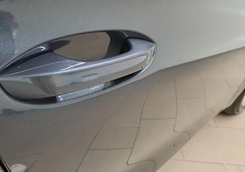 Gros plan sur la poignée de porte côté droit d’une SEAT LEON 2025 gris magnétique avec peinture métallisée brillante.