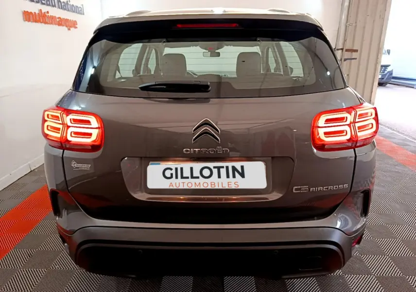 Vue arrière d’un Citroën C5 Aircross gris foncé avec feux arrière LED allumés dans un garage.