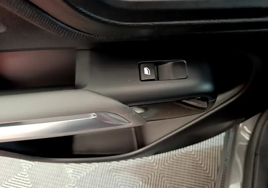 Gros plan sur la commande de lève-vitre côté gauche d'une Citroën C5 Aircross gris foncé, avec poignée intérieure argentée.