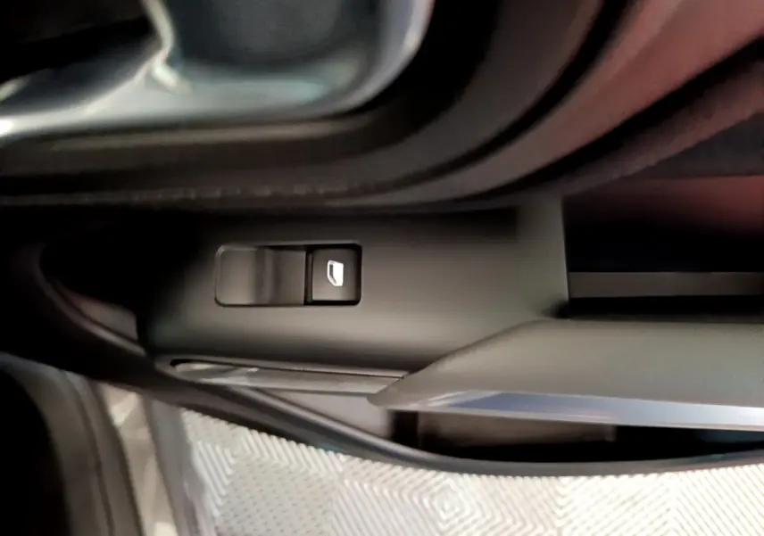 Gros plan sur le bouton de verrouillage des vitres côté conducteur d’un Citroën C5 Aircross gris foncé, intérieur noir.