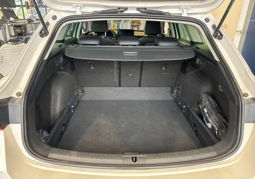 Coffre ouvert vu de l'arrière d'une CUPRA LEON ST blanche 2024, avec cache-bagages et intérieur noir.