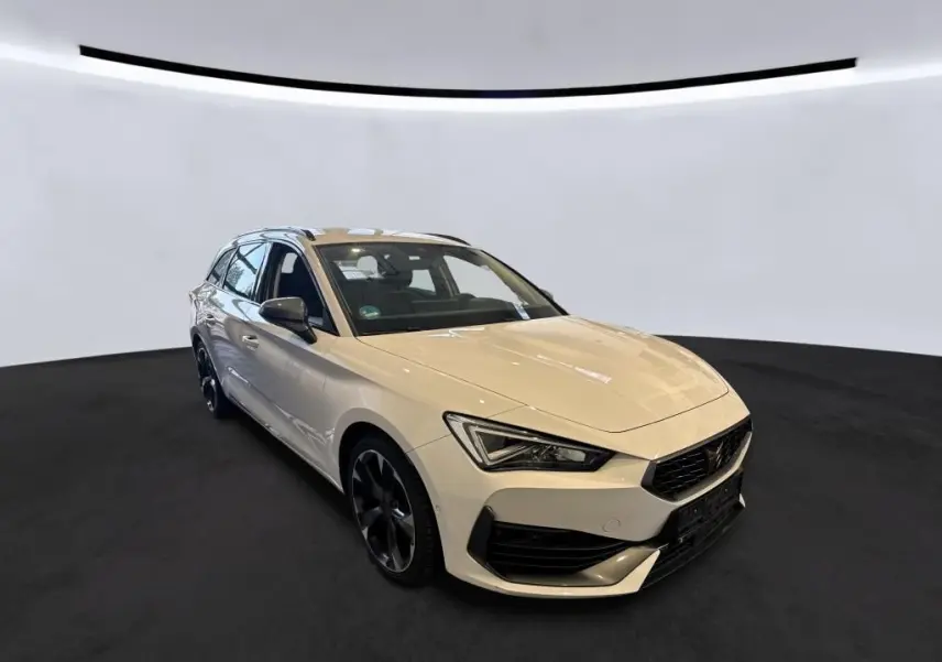 Vue 3/4 avant droite d'une CUPRA Leon ST blanche 2024 avec jantes noires et calandre distinctive.