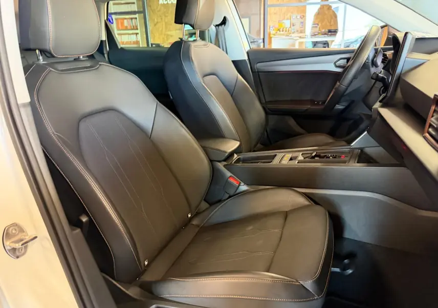 Vue plongeante sur la console centrale noire avec porte-gobelets et prise 12V du CUPRA LEON ST 2024 intérieur.