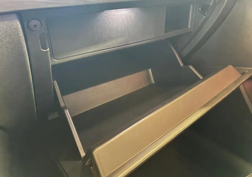 Gros plan sur la boîte à gants ouverte de la CUPRA LEON ST 2.0 TDI 150 DSG7, intérieur noir visible.