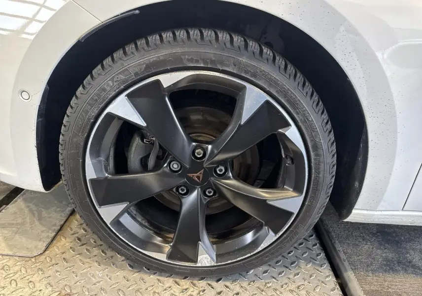 Gros plan sur la roue avant droite d'une CUPRA LEON ST blanche, avec jante alliage noire et argentée au design sportif.