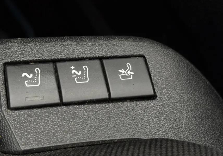 Gros plan sur les boutons de réglage des sièges chauffants et rabattables dans une Citroën C4 Spacetourer gris foncé.