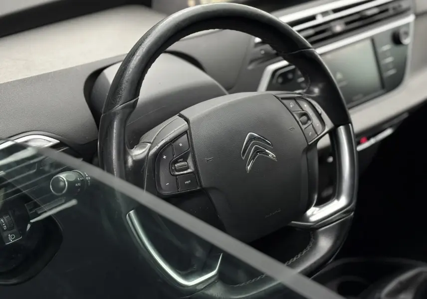 Gros plan sur le volant en cuir noir du Citroën C4 Spacetourer 2018, avec commandes intégrées et tableau de bord flou.