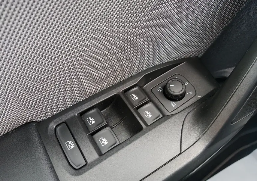 Gros plan sur les commandes de lève-vitres et réglage des rétroviseurs côté conducteur d'une SEAT LEON ST gris 2022.