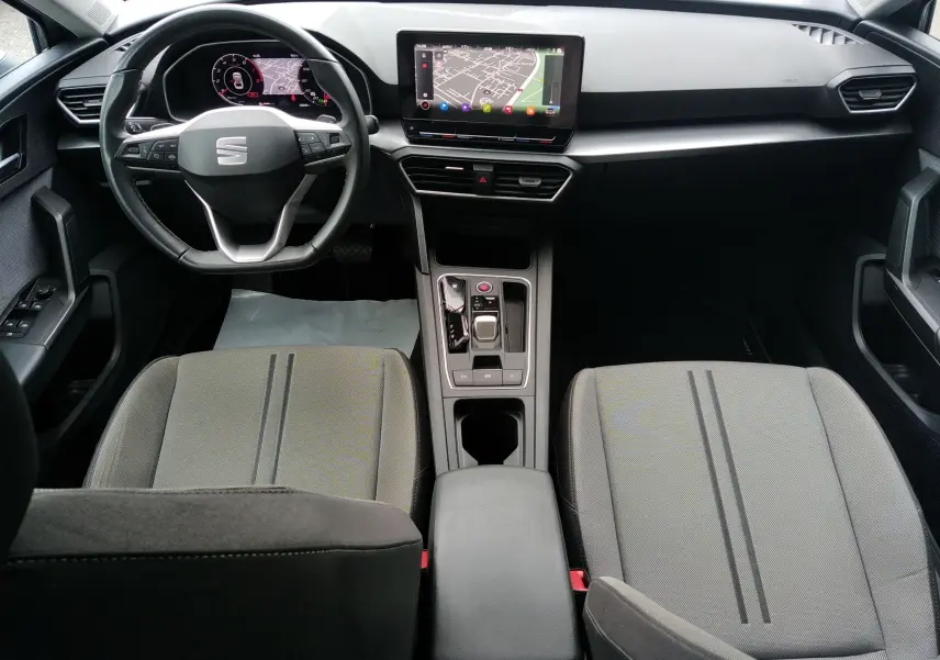 Intérieur du SEAT LEON ST gris 2022 vu de dessus, tableau de bord moderne avec écran tactile et volant multifonction.