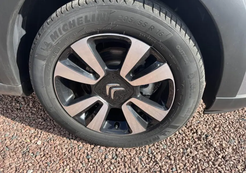 Gros plan sur la roue avant gauche d'une Citroën C3 gris avec jante alliage bicolore et pneu Michelin.