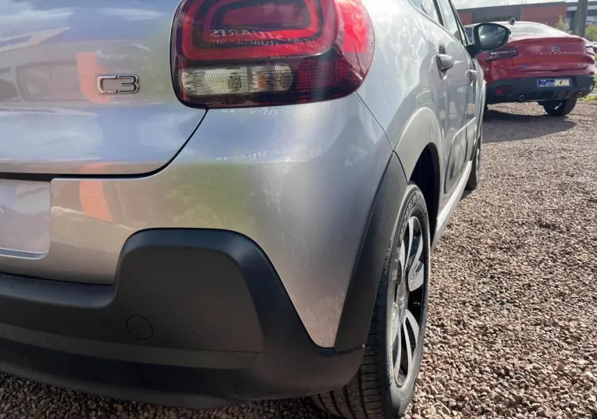 Vue 3/4 arrière droite d'une Citroën C3 gris nacré avec feux arrière distinctifs et protections noires sur le pare-chocs.
