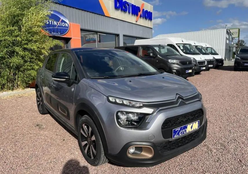 Citroën C3 gris en 3/4 avant droit, avec projecteurs LED et détails noirs contrastants sur carrosserie nacrée.
