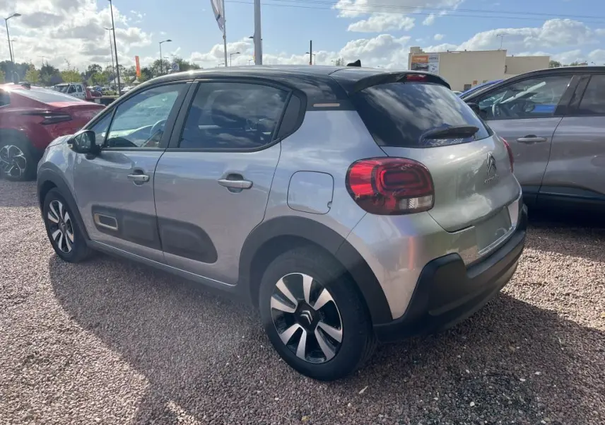 Vue 3/4 arrière droite d'une Citroën C3 gris nacré avec toit noir et protections latérales noires.