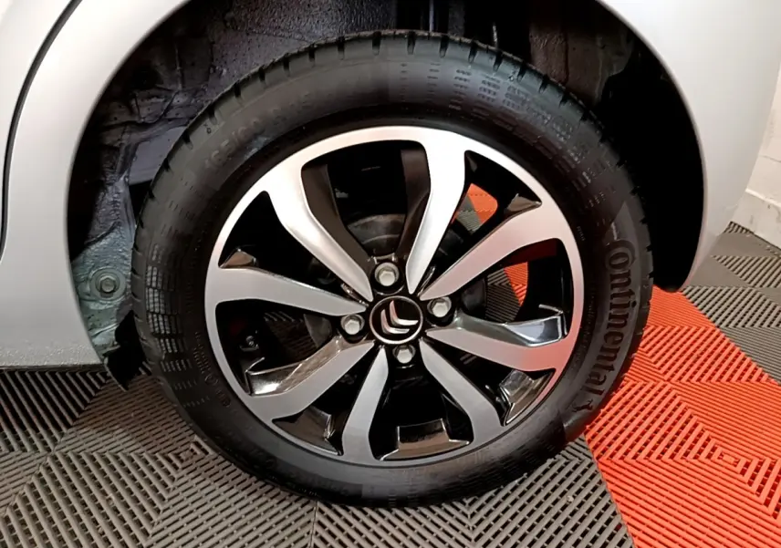 Gros plan sur la roue avant droite gris clair d'une Citroën C1 avec jante alliage noire et argentée.