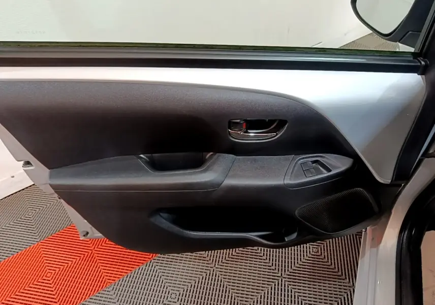 Vue intérieure de la porte avant gauche gris clair de la Citroën C1 avec commandes de vitres et poignée chromée.