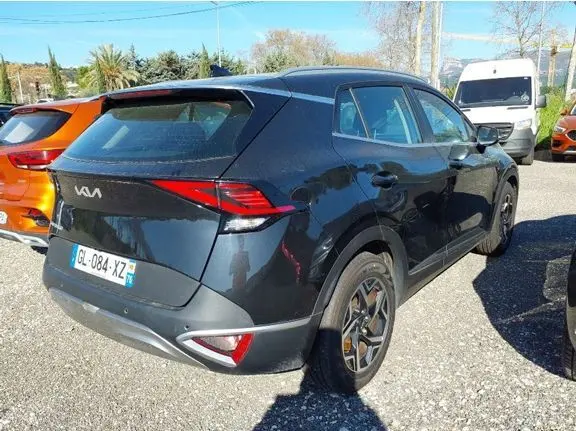 Vue 3/4 arrière droite d'un KIA Sportage noir 2022, hybride diesel, avec feux arrière LED et jantes alliage.