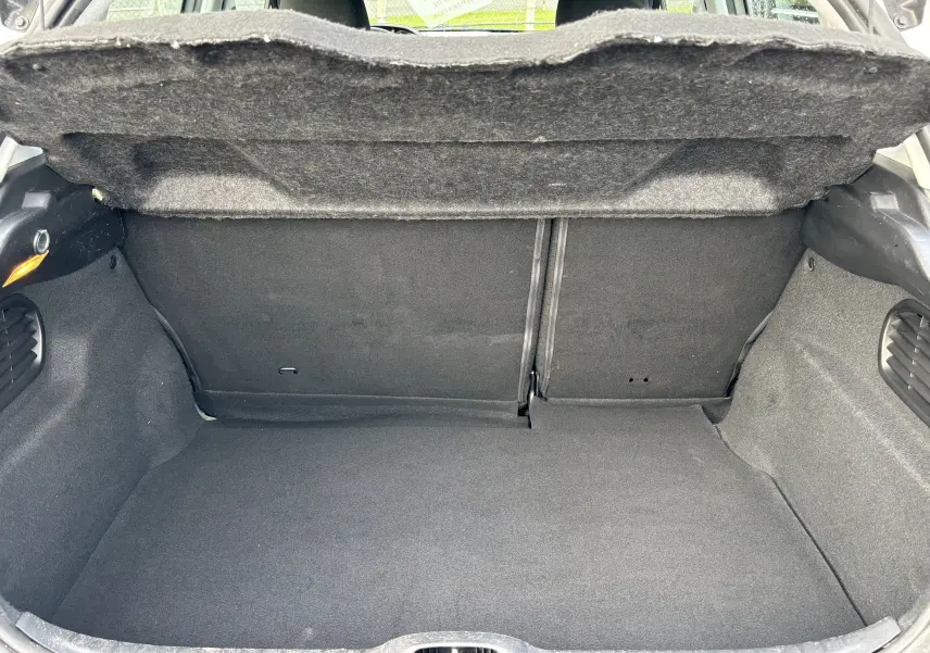 Coffre ouvert de la Peugeot 208 gris argent 2017, vue intérieure montrant l'espace de chargement et la moquette noire.