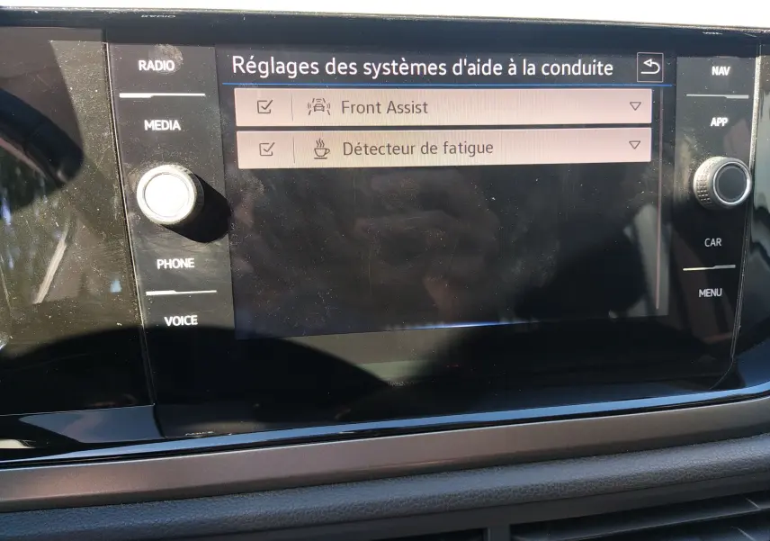 Écran tactile central du tableau de bord d'une Volkswagen Polo blanche 2021 affichant les réglages d'aide à la conduite.