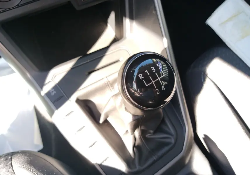 Le levier de vitesses manuel noir de la Volkswagen Polo blanche 2021, vu en gros plan dans l'habitacle.