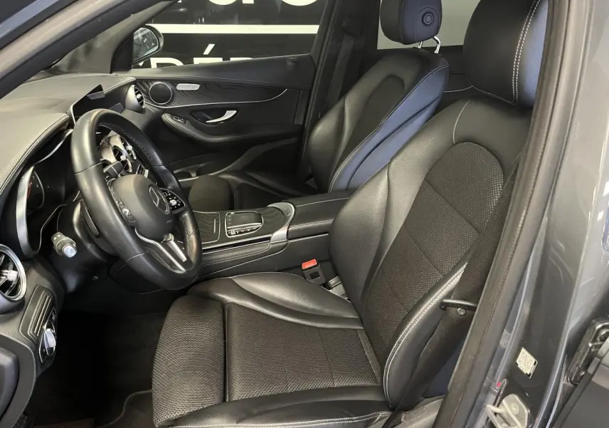 Intérieur côté conducteur d'une Mercedes GLC 200 gris, sièges noirs en cuir et console centrale visible.