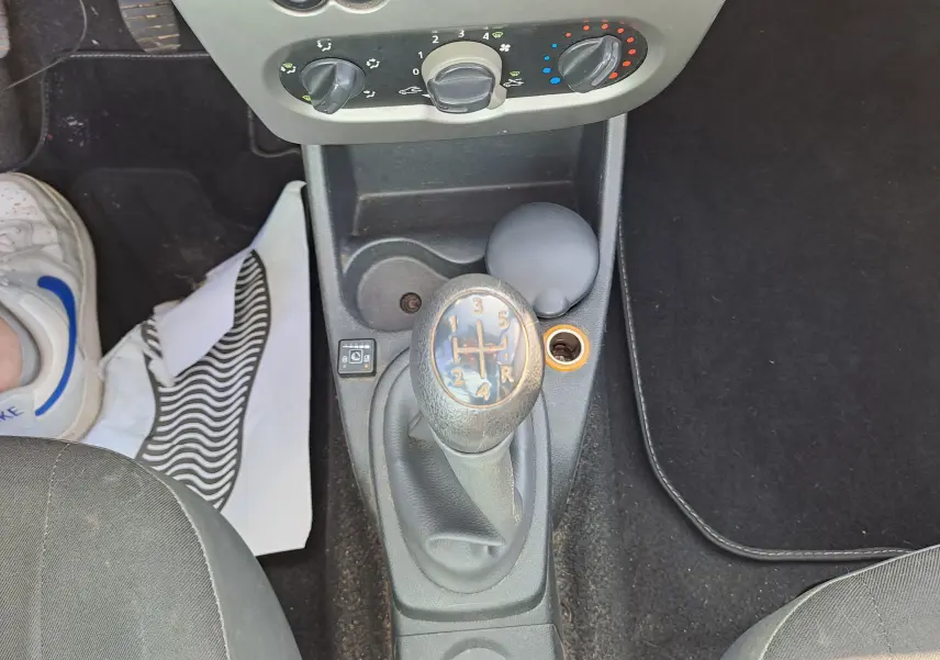 Le levier de vitesses manuel central d'une Dacia Sandero 2010 avec commandes de climatisation en haut.