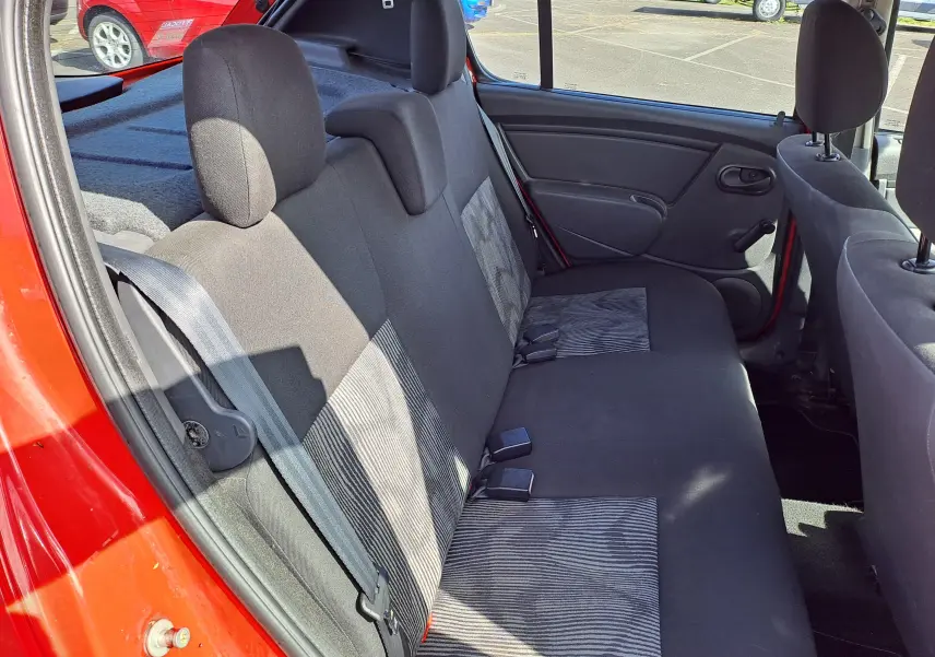 Vue intérieure côté gauche des sièges arrière en tissu noir et gris d'une Dacia Sandero rouge de 2010.
