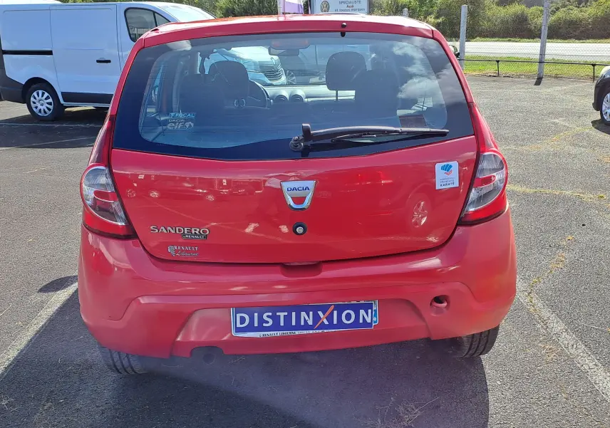 Vue arrière d'une Dacia Sandero rouge de 2010 avec logo et autocollant Fédération Française de Karaté.