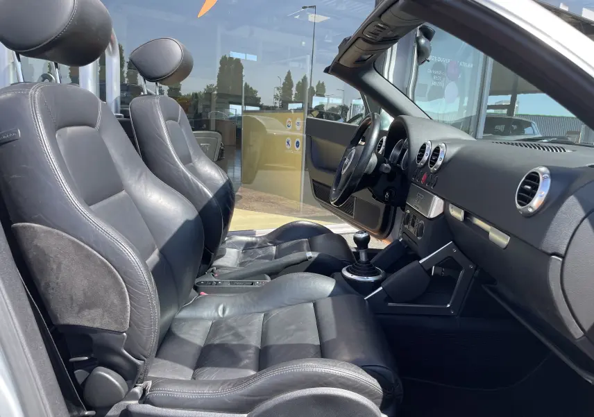 Intérieur noir cuir de l'Audi TT Roadster 1.8T 180 de 2002, vue côté conducteur avec tableau de bord et levier manuel visible.