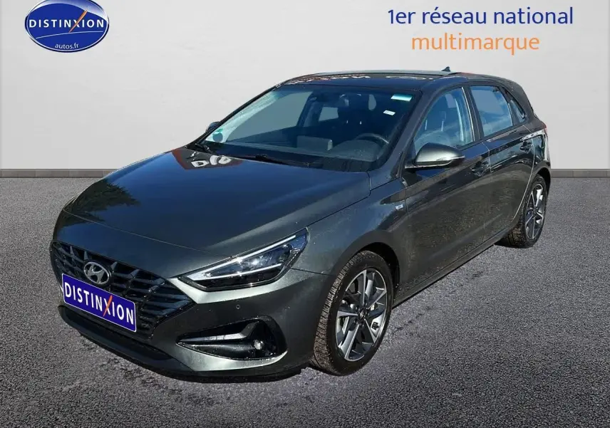 Vue 3/4 avant droit d'une Hyundai i30 gris argent 2024 avec jantes alliage et phares LED distinctifs.