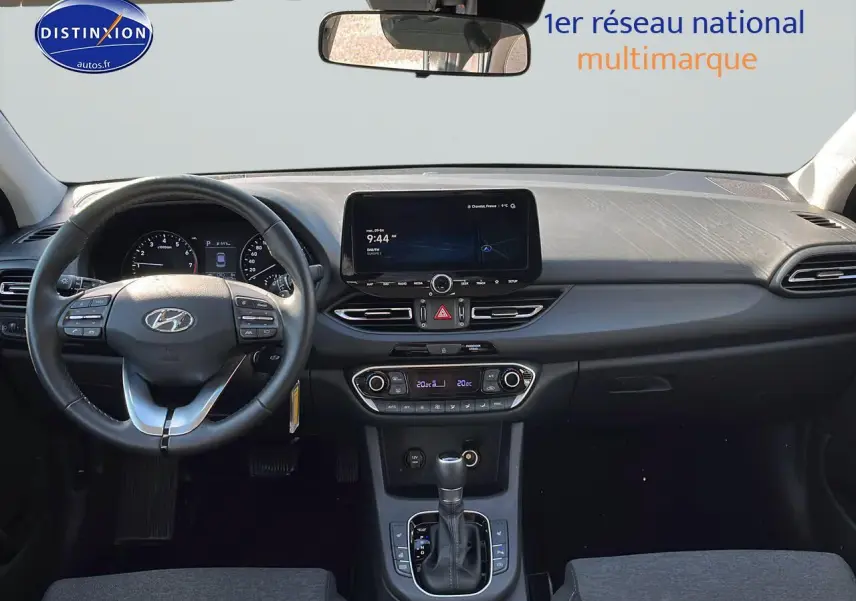 Intérieur de la Hyundai i30 2024 en gris, vue frontale du tableau de bord avec écran tactile et volant cuir multifonction.